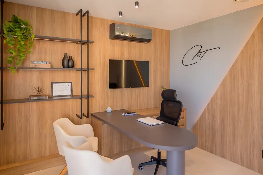 Mesa de atendimento com cadeiras claras, painel de madeira e a assinatura MT na parede